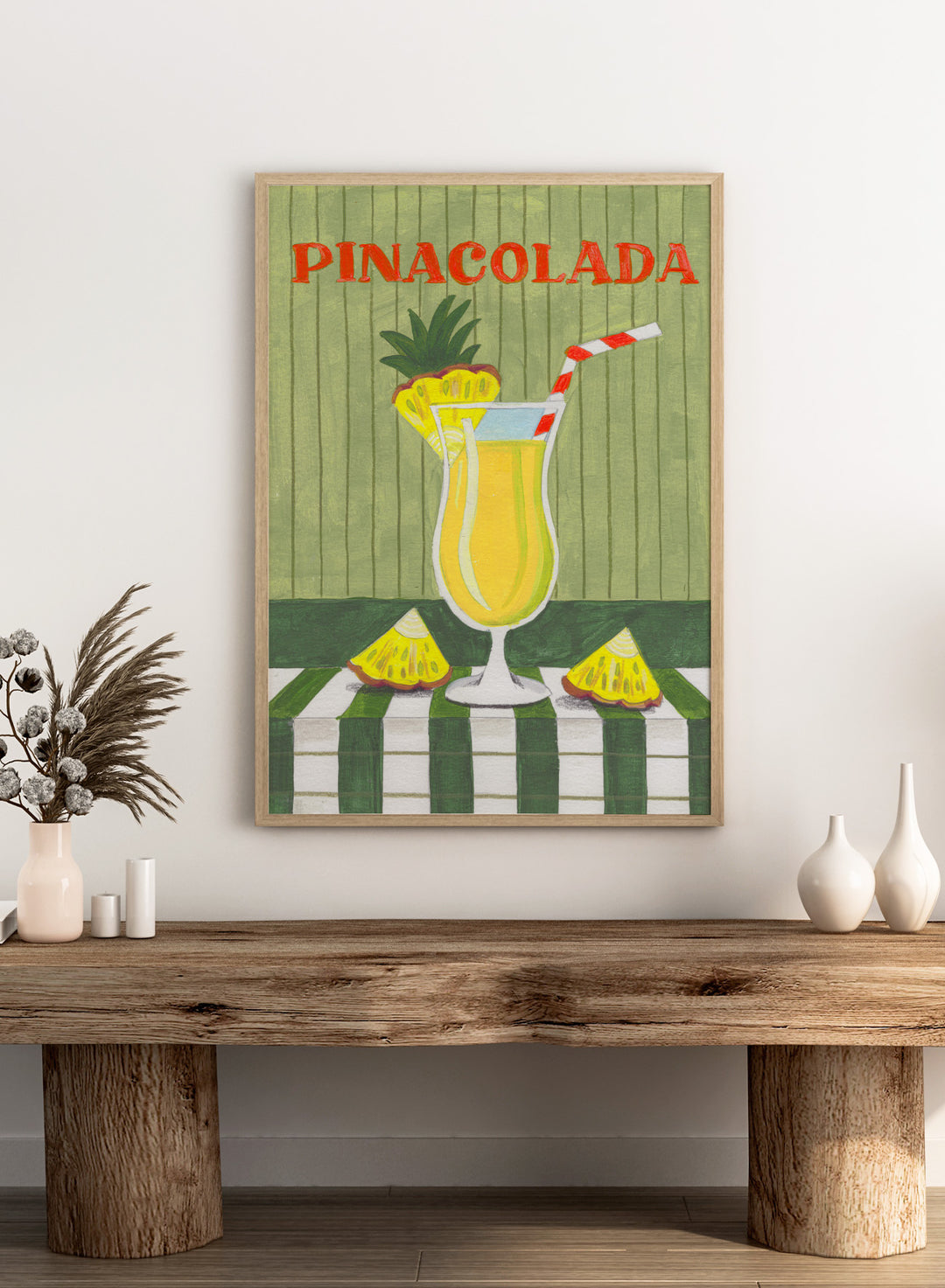Illustration of a pina colada drink with pineapple slices on a checkered tablecloth. Piña Colada Summer Drink by Caroline Bonne Müller is a fine art print and wall poster of a pineapple cocktail with striped straw and green table setting.