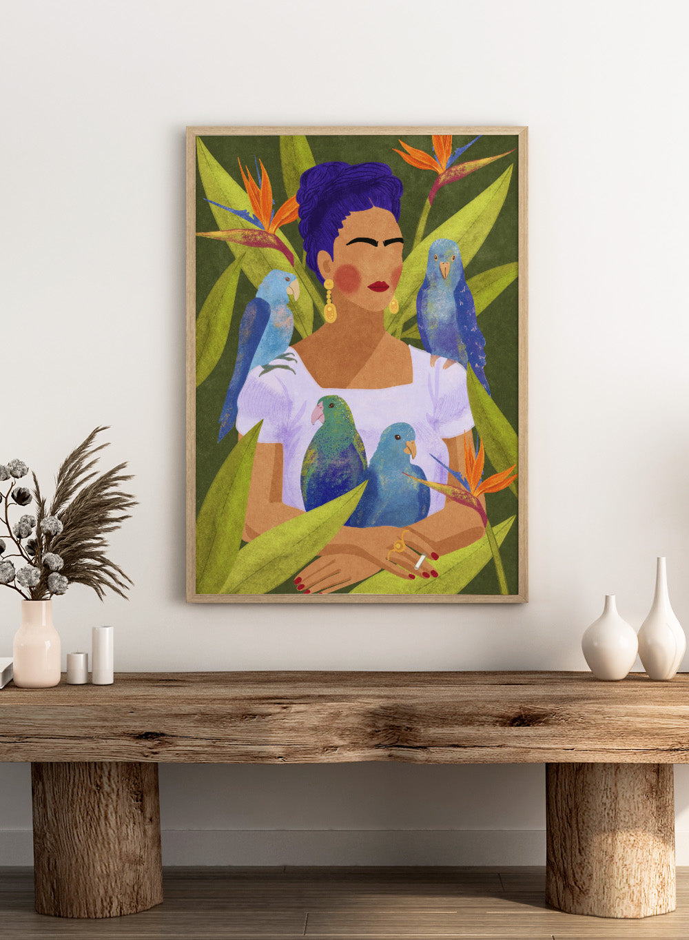 Artistic depiction of a woman with blue hair surrounded by parrots and tropical plants. Frida and Birds by Raissa Oltmanns is a modern Frida Kahlo inspired art print with tropical birds and bold botanical wall poster design.