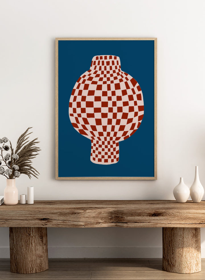 A stylized graphic illustration of a vase with a red and cream checkerboard pattern, set against a dark blue background. Optical Checkered Vase by The Art Concept is a modern still life art print featuring a red checkered vase on a deep blue background in a bold graphic style.