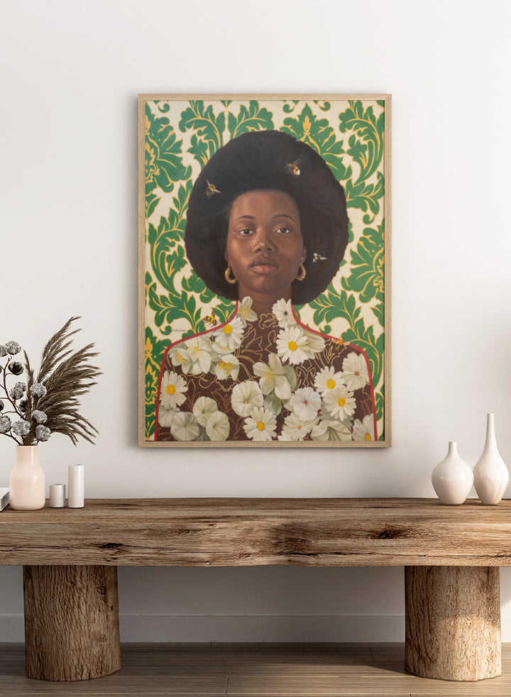 A stylized portrait artwork of a Black woman with an afro hairstyle, wearing gold hoop earrings and a brown top covered in white daisy flowers, set against a green and cream damask patterned background with small bees visible. Shop Afro Floral Portrait by Damilare Jamiu, a contemporary portrait wall art print featuring a woman with afro hair, floral details, bees, and rich green tones.