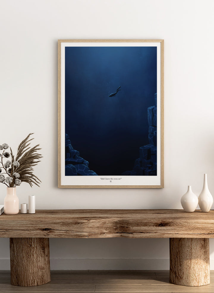 A framed art print featuring a dark blue underwater scene with a diver floating in the center, flanked by glowing blue rock formations. Shop Deep Blue Diver by Jake Waldron, a minimalist diving wall art print featuring a lone deep-sea diver, underwater cliffs, and dramatic navy blue tones.