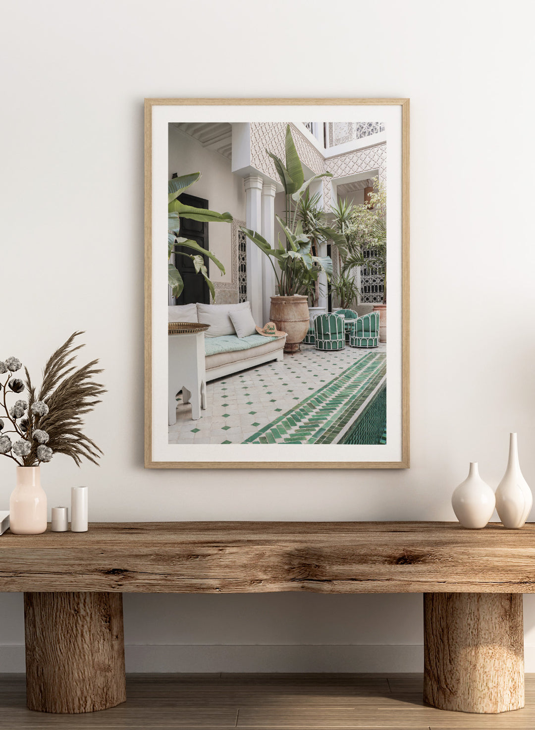 Outdoor patio with white sofa, green chairs, and potted plants in a decorative courtyard. Moroccan Riad Courtyard Oasis by Henrike Schenk is a Morocco photography print of a riad courtyard with tropical plants, tilework, and interior decor.