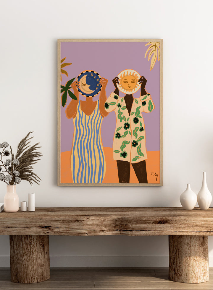 Two people holding celestial objects against a purple background. Sun and Moon by Arty Guava is a playful contemporary art print featuring female figures, celestial motifs, bold color, tropical influences, and modern illustration.