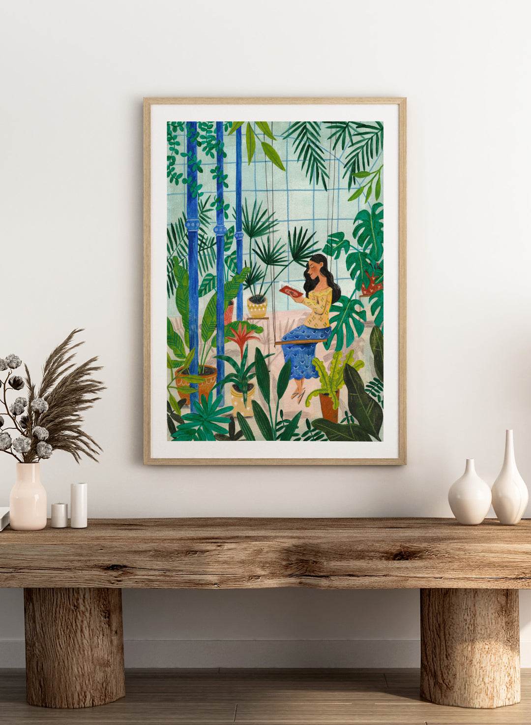 Woman sitting among plants in a room with bamboo and various greenery. Botanical Greenhouse Reader by Caroline Bonne Müller is a fine art print and wall poster featuring a woman reading in a lush indoor garden filled with tropical plants.