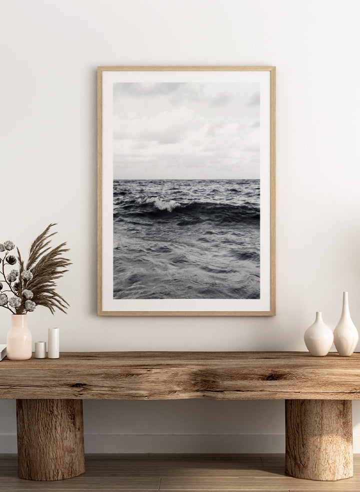 Black and white photographic art print of ocean waves under a cloudy sky. Endless Waves by Shot by Clint black-and-white ocean photography print featuring rolling water, textured surf, cloudy skies, and dramatic coastal movement.