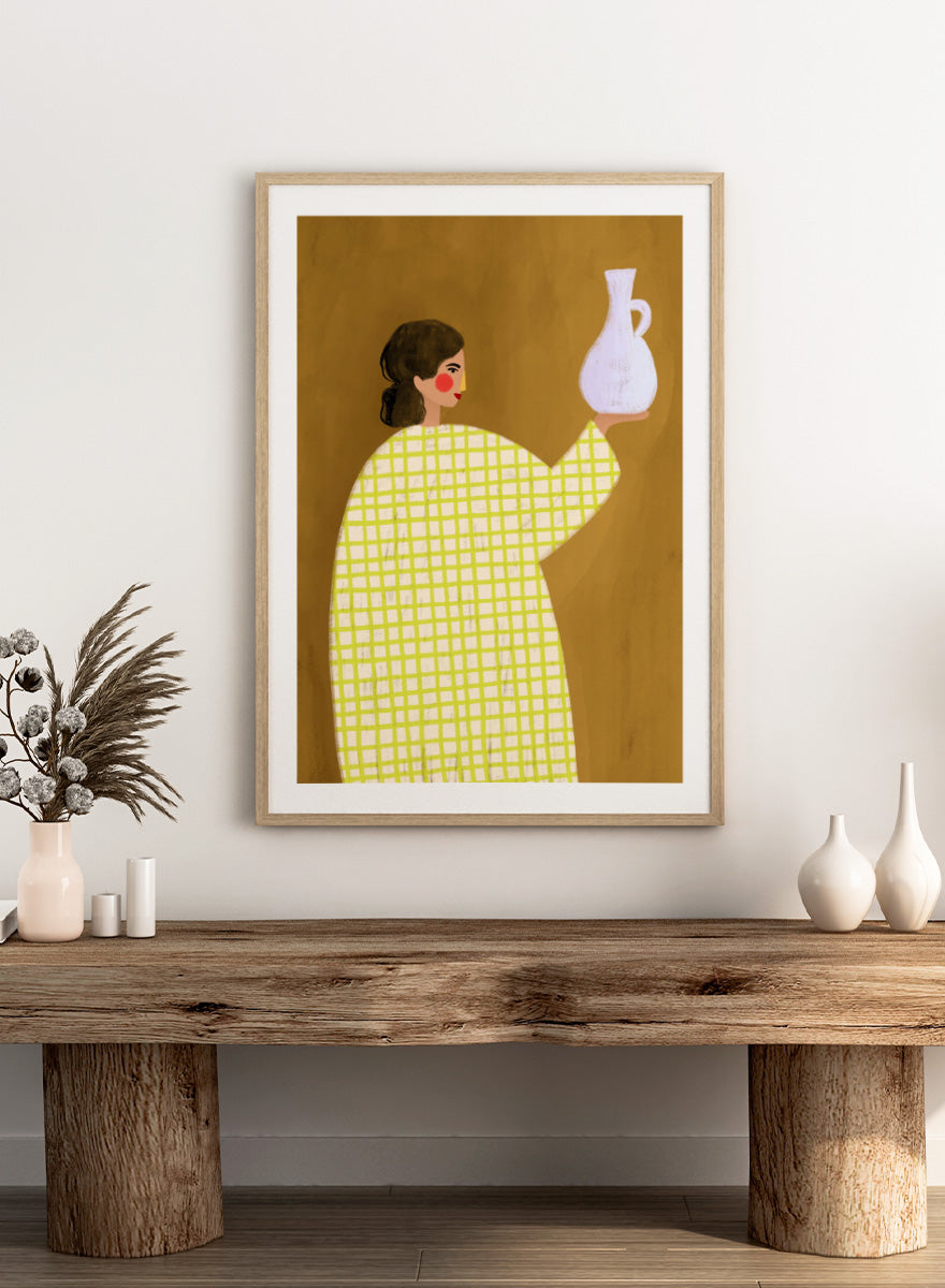 A framed art print featuring a stylized illustration of a woman in a yellow and white checkered dress holding a white jug against a warm brown background. Woman Holding Pottery by Bea Müller art print featuring a woman with a white ceramic jug, bold green checks, and warm mustard tones for modern decor.