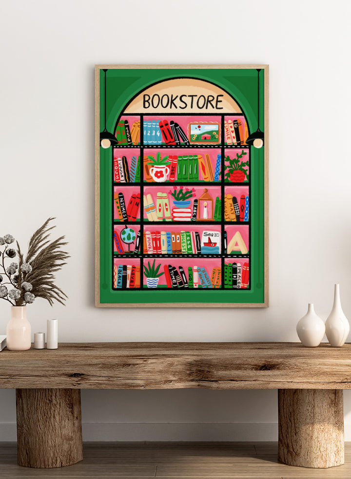 A colorful illustrated storefront sign for a bookstore, showing an arched window with shelves of books, plants, and small objects in bright pink, green, orange, blue, and yellow tones. Shop Charming Bookstore Shelf by Nidhi Kachhadiya, a colorful bookstore wall art print with bookshelves, plants, graphic shapes, and bold pink and green tones.