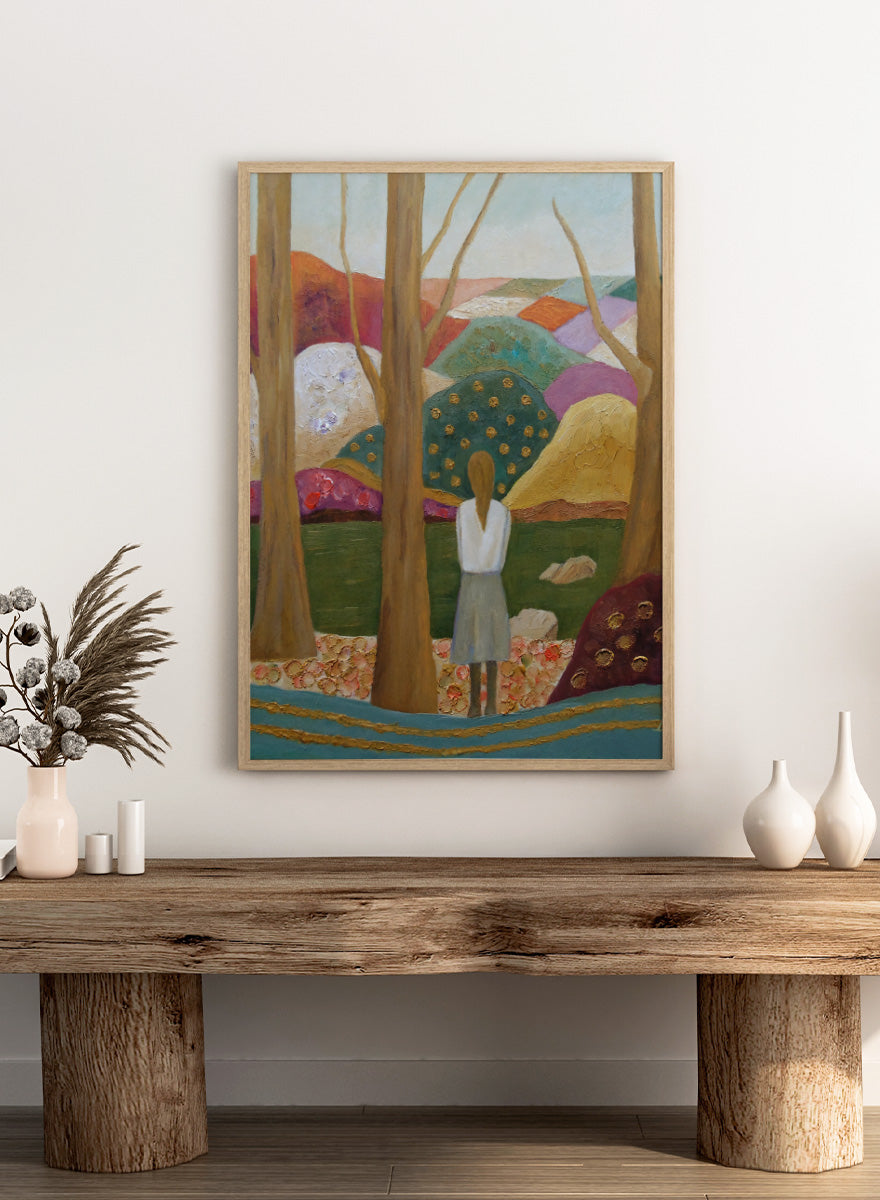 An expressive painting of a woman seen from behind standing among tall trees in a stylized landscape with colorful hills, patches of green, purple, pink, blue, and gold accents. Shop Woman Among Vibrant Hills by Angeles M. Pomata, a colorful landscape and portrait art print featuring a woman, rolling hills, trees, and earthy tones.