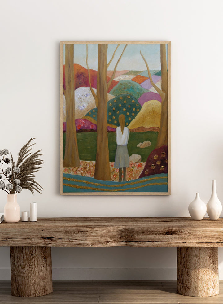 An expressive painting of a woman seen from behind standing among tall trees in a stylized landscape with colorful hills, patches of green, purple, pink, blue, and gold accents. Shop Woman Among Vibrant Hills by Angeles M. Pomata, a colorful landscape and portrait art print featuring a woman, rolling hills, trees, and earthy tones.