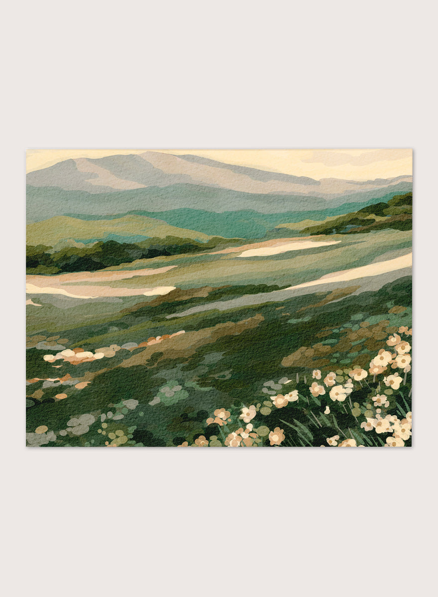 Shop Wildflower Mountain Landscape by Nikita Jariwala, a mountain wall art print with rolling green hills, cream wildflowers, and soft sage and blue-gray tones.