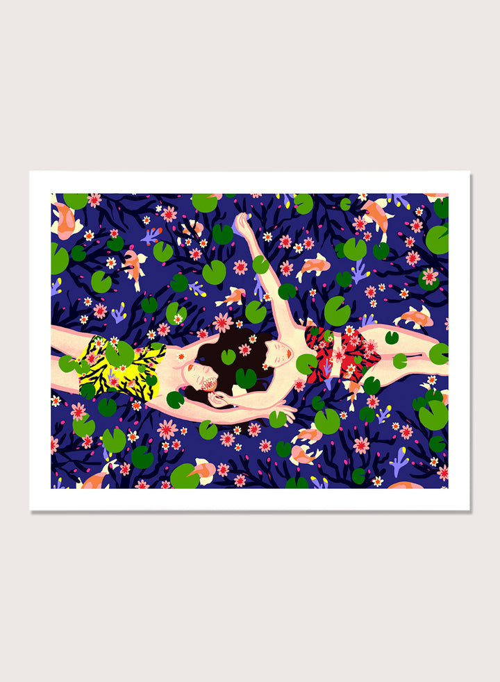 A framed art print featuring a stylized illustration of a woman lying on a dark blue background covered with green lily pads and pink flowers. Serene Night Float by Ceyda Alasar friendship art print featuring three women floating among lily pads, flowers, and fish in a deep blue pond.
