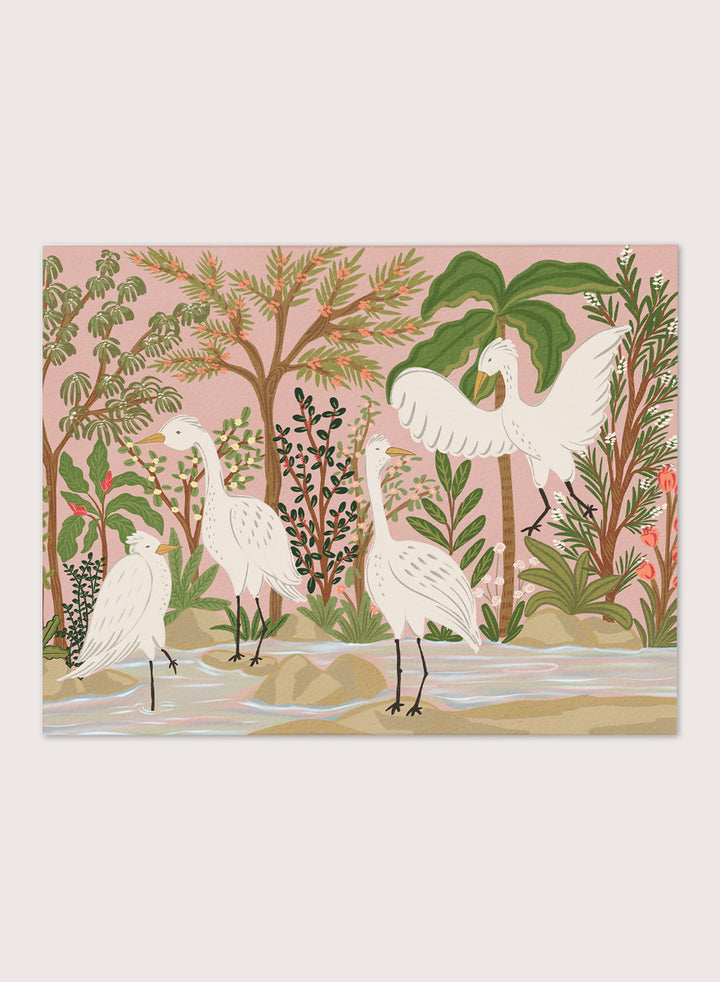 A framed art print featuring a stylized illustration of four white cranes in a tropical landscape with palm trees, green foliage, and a pink sky, displayed on a light beige wall. Shop Peaceful Jungle Egrets by Nikita Jariwala, a tropical bird wall art print featuring white egrets, lush greenery, botanical detail, and soft pink tones.a