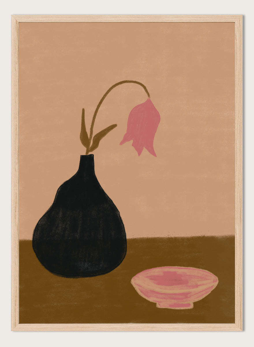 A minimalist still life painting featuring a black pear-shaped vase with a single drooping pink flower, alongside a pink bowl, set against a warm beige background and a brown tabletop. Minimal Pink Still Life by The Art Concept still life art print featuring a black vase, drooping pink flower, small bowl, and warm earthy tones.