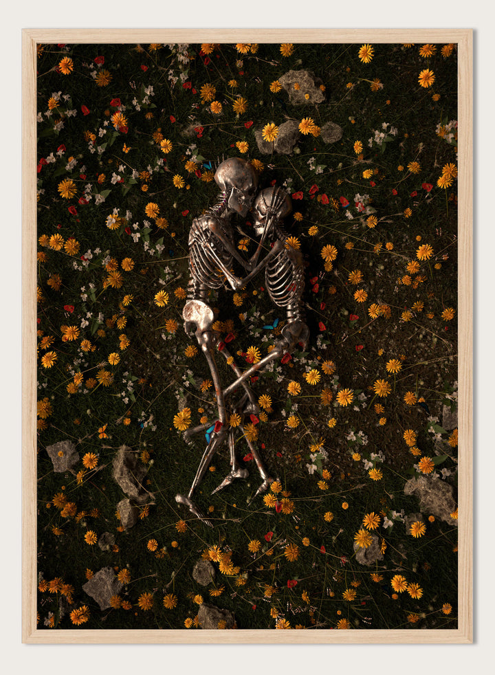 Skeletons In Love by Nicebleed is a surreal skeleton couple art print featuring intertwined skeletons in a floral field, modern aesthetic wall poster.
