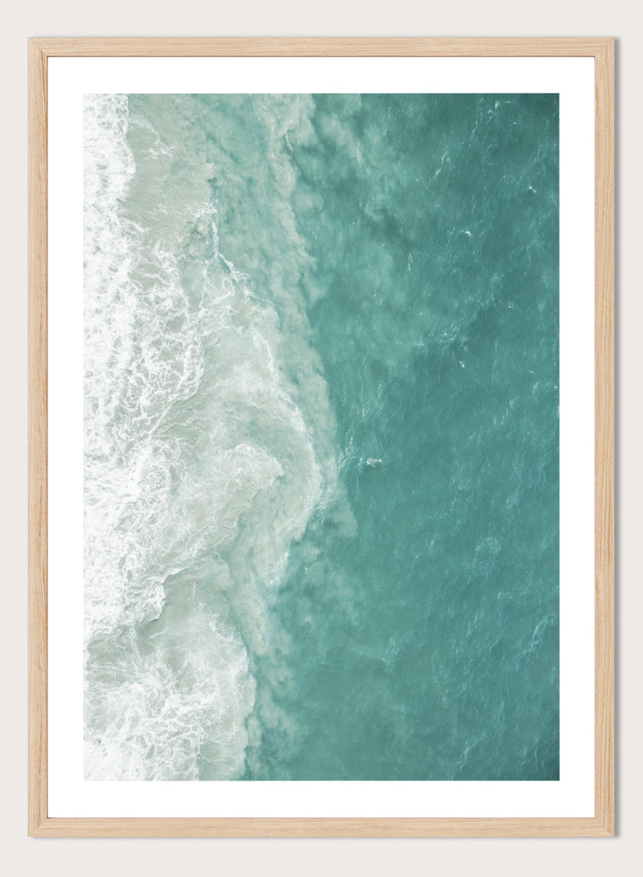 A framed aerial photograph of ocean waves, showing white foam breaking into turquoise and teal water. Ocean’s Edge by Shot by Clint aerial ocean photography print featuring turquoise water, white surf, and layered coastal movement.