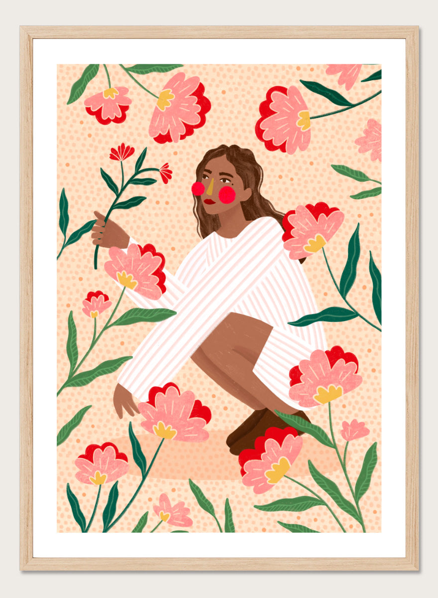 A framed art print featuring a stylized illustration of a woman in a white striped sweater surrounded by pink and red flowers on a peach background. Woman in Floral Garden by Bea Müller floral art print featuring a woman surrounded by oversized pink flowers, green leaves, and playful botanical details.