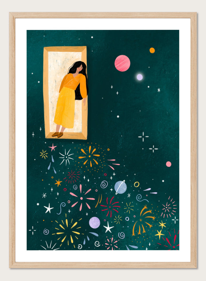 A framed art print featuring a whimsical illustration of a woman in a yellow dress standing in a mirror, with her reflection spreading colorful fireworks and space-themed motifs like planets and stars across a dark teal background. Shop Girl and Cosmic Fireworks by Bea Müller, a figurative wall art print poster featuring a woman, planets, stars, and colorful cosmic fireworks in deep green tones.