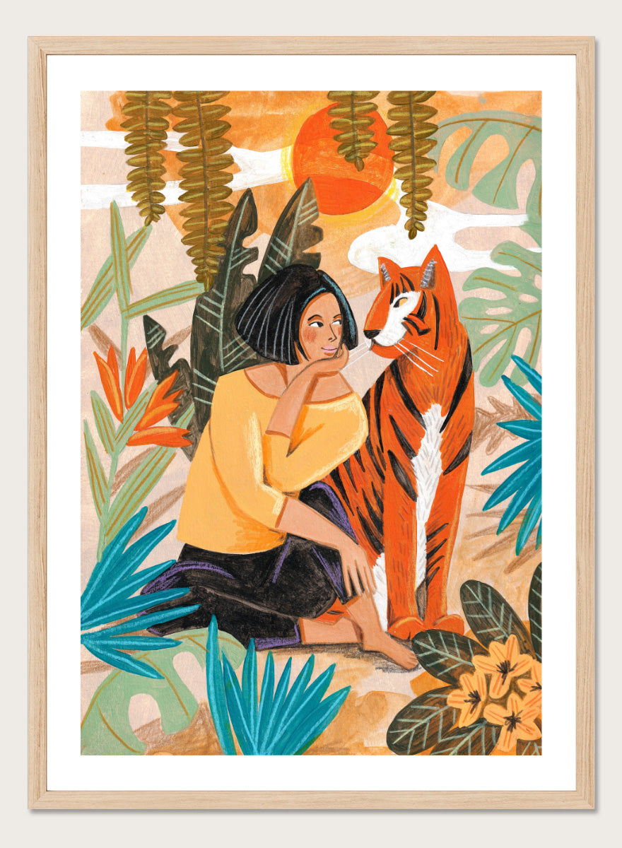 A framed art print featuring a stylized illustration of a woman in a yellow top and black skirt sitting beside an orange tiger, surrounded by tropical leaves and a warm orange sky. Woman with Tiger by Caroline Bonne Müller tropical art print featuring a woman beside a tiger among lush foliage, bold color, and hand-drawn texture.