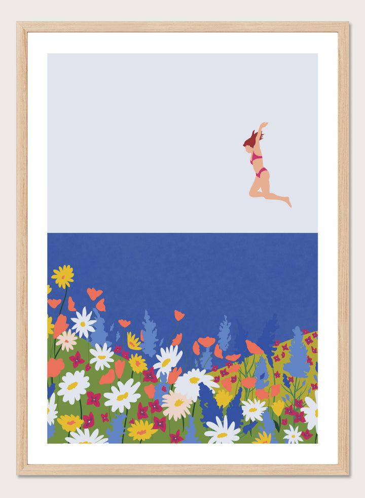 A framed art print featuring a minimalist illustration of a woman in a pink bikini jumping into a blue sea with a colorful wildflower meadow below. Wildflower Summer Jump art print by Ceyda Alasar features a joyful figure above colorful blooms, bringing playful summer energy to your walls.