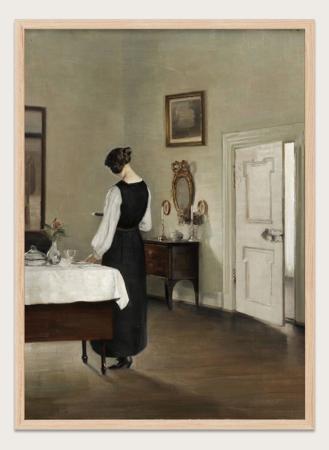 Woman in a black dress standing in a room with a table and mirror. In the Dining Room by Carl Holsøe is a vintage Danish interior art print featuring a woman in a softly lit dining room with muted tones and classic Scandinavian style.
