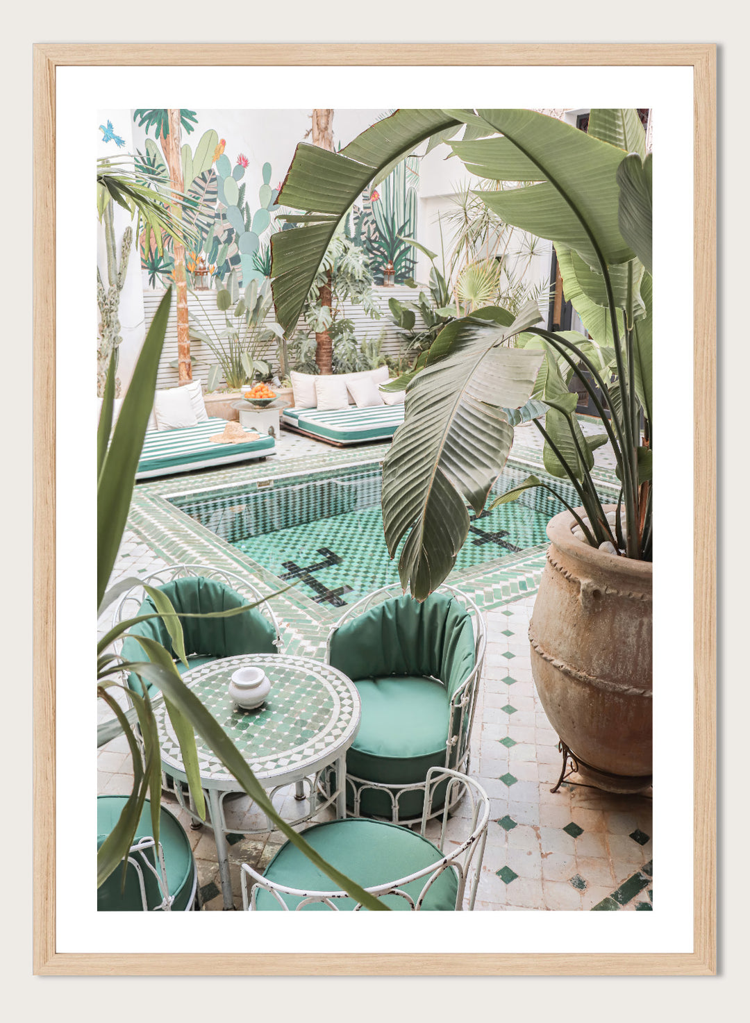 Outdoor patio with pool, green chairs, and potted plants. Green Courtyard Oasis by Henrike Schenk is a Morocco travel photography print showing a lush riad courtyard with green tilework, tropical plants, and poolside interiors.