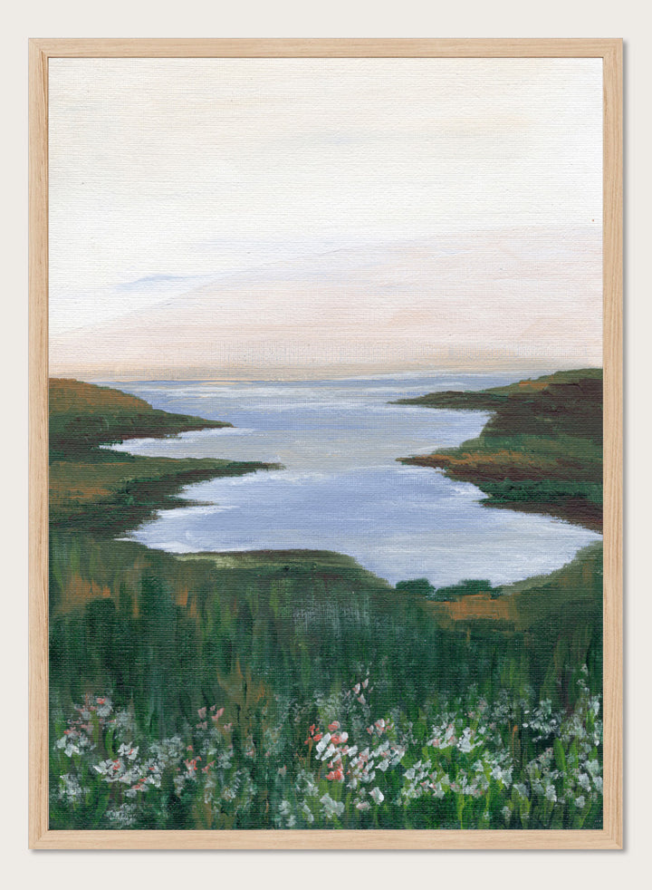 A landscape painting of a winding river or inlet between green hills, with a pale sky above and wildflowers in the foreground. Shop Wildflower Coast View by Nikita Jariwala, a coastal landscape wall art print poster featuring ocean views, green cliffs, wildflowers, and soft blue tones.