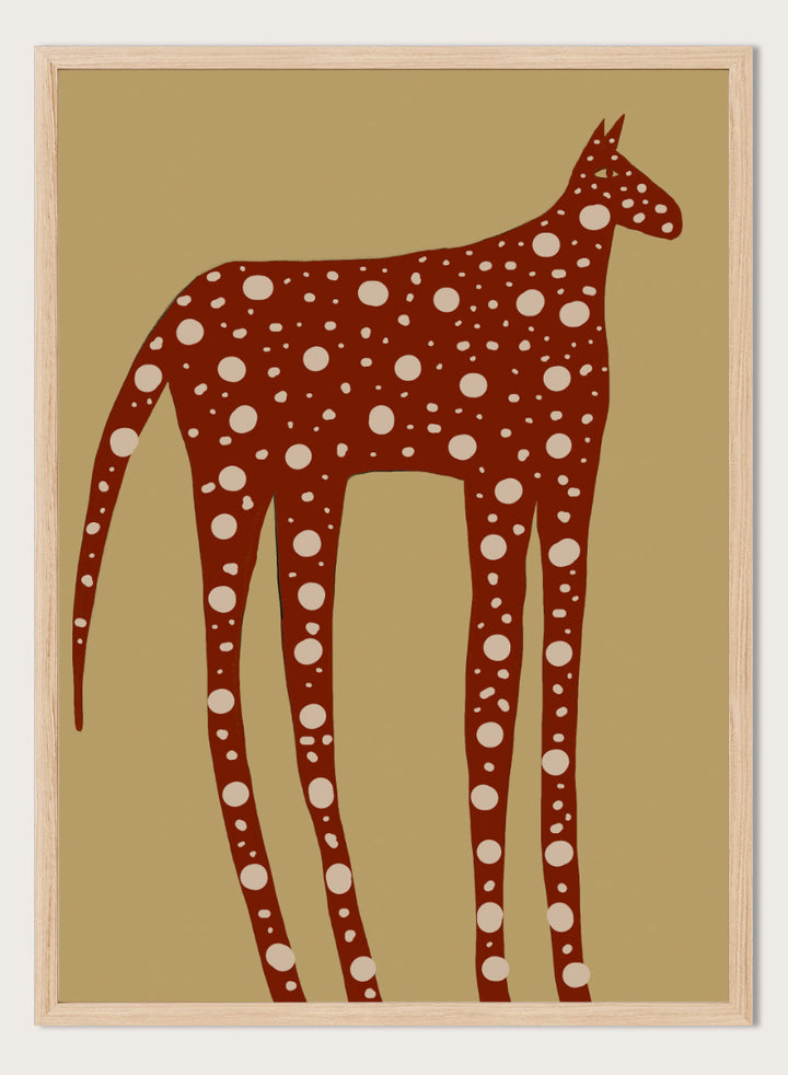 A stylized art print of a giraffe in reddish-brown with white spots, set against a tan background. Spotted Earthy Creature by The Art Concept animal art print featuring a long-legged rust-colored figure with cream spots on a muted tan background.