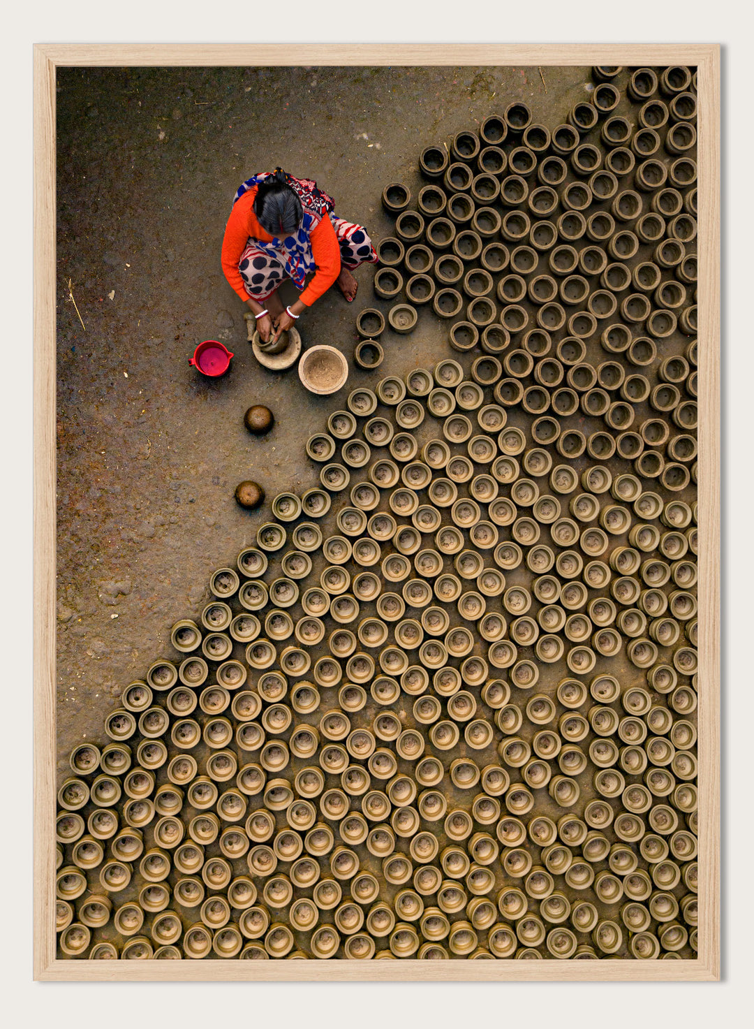 Person working with clay pots on a textured surface. Pot Making by Azim Khan Ronnie aerial photography print showing clay pots drying in Bangladesh village, traditional craft wall art poster