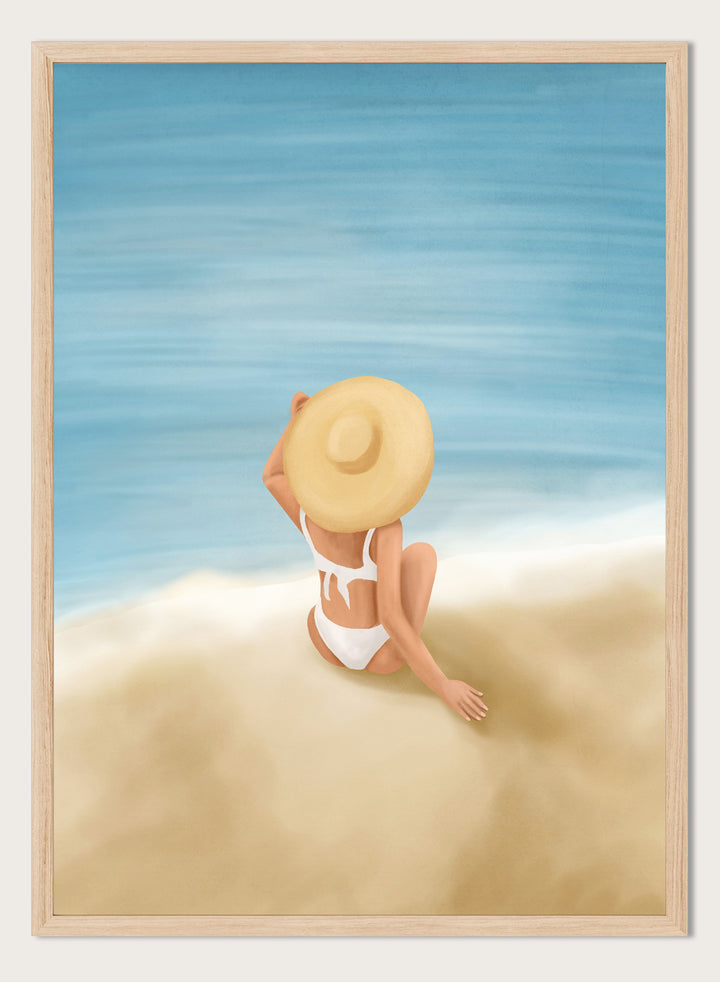 Woman in a white bikini and sun hat sitting on sand looking at ocean. Ocean View Relaxation by Flow Line is a coastal wall art print featuring a woman by the ocean, soft blue tones, beach decor, and relaxed summer style.