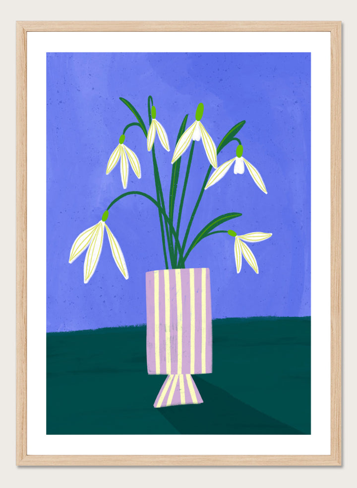 A framed art print featuring a stylized illustration of white snowdrops with green stems in a lavender and cream striped vase, set against a blue and dark green background. Snowdrops in Striped Vase by Bea Müller fine art print featuring white snowdrops, a lilac striped vase, and a deep blue background.