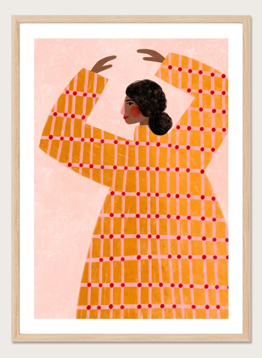 A framed art print featuring a stylized illustration of a woman in profile wearing a bright orange dress with a red grid pattern, set against a pale pink background. Dancing Woman in Orange by Bea Müller premium fine art print featuring a bold figure, warm orange tones, and a playful graphic composition.