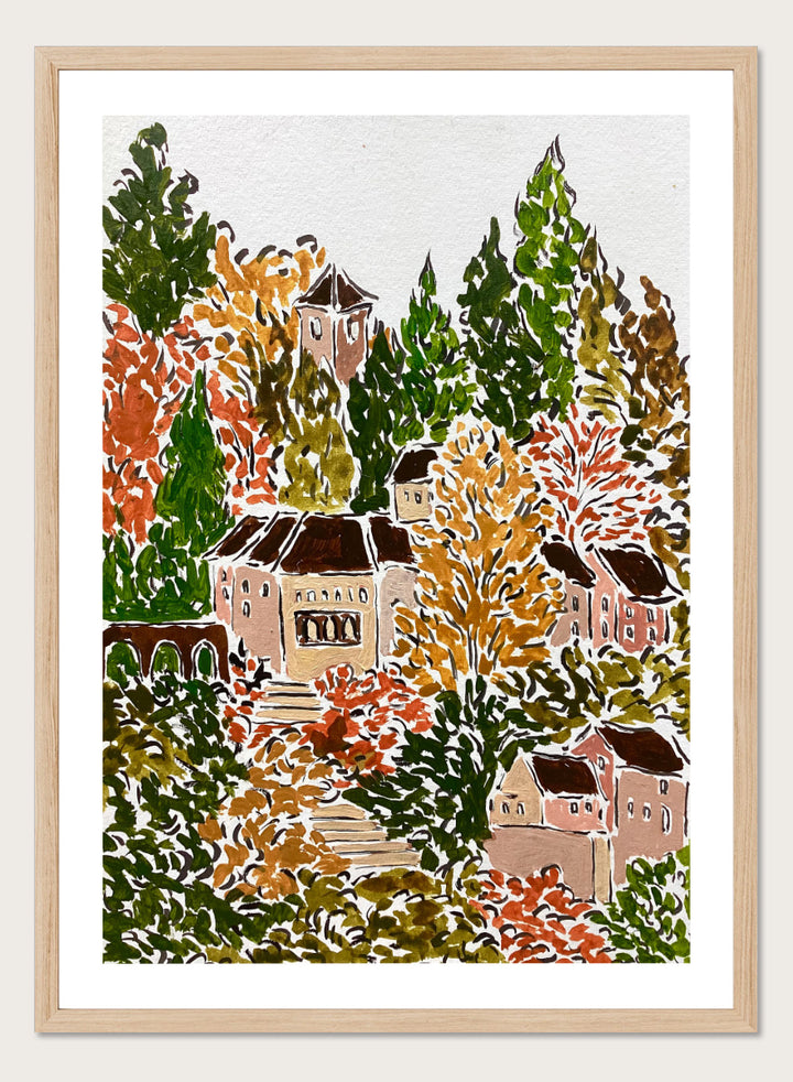 A framed art print featuring a hand-drawn, stylized landscape of a hillside village with beige buildings, brown roofs, and dense trees in green, yellow, orange, and red tones. Shop Autumn Hillside Village by Rushati Chowdhury, a colorful autumn landscape art print with hillside homes, winding steps, dense trees, and warm fall tones.
