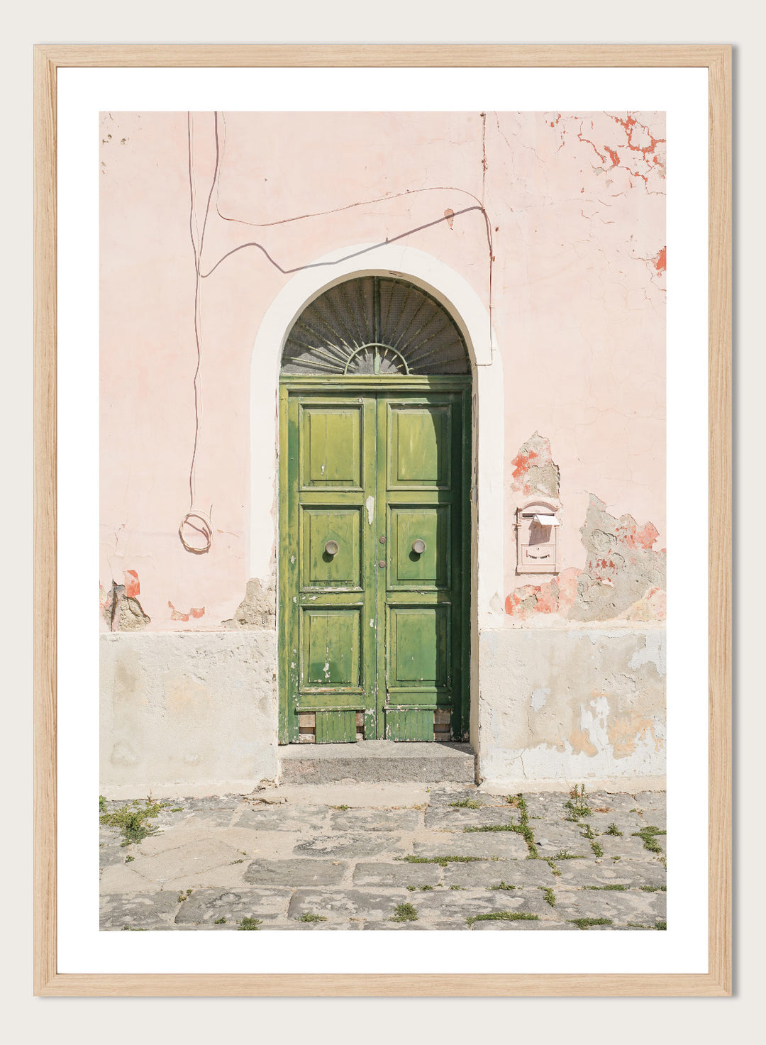 Green door on a pink wall with peeling paint. Old World Green Door by Henrike Schenk features a vintage European doorway, weathered architecture, pastel walls, travel photography, and wall art.