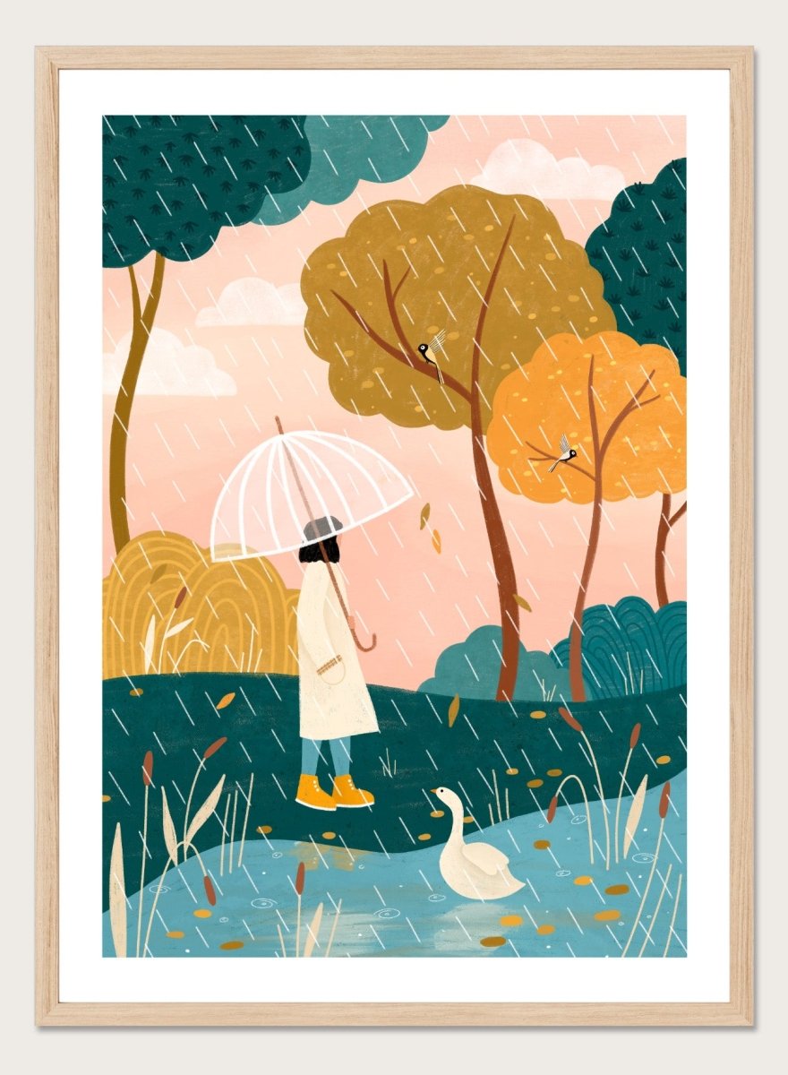 A framed art print featuring a whimsical illustration of a person holding a clear umbrella in the rain near a pond with a white goose, surrounded by stylized trees in teal, mustard, and orange tones. Walking In Autumn Rain by Bea Müller premium framed fine art print featuring a woman with an umbrella beside a pond in a colorful rainy landscape.