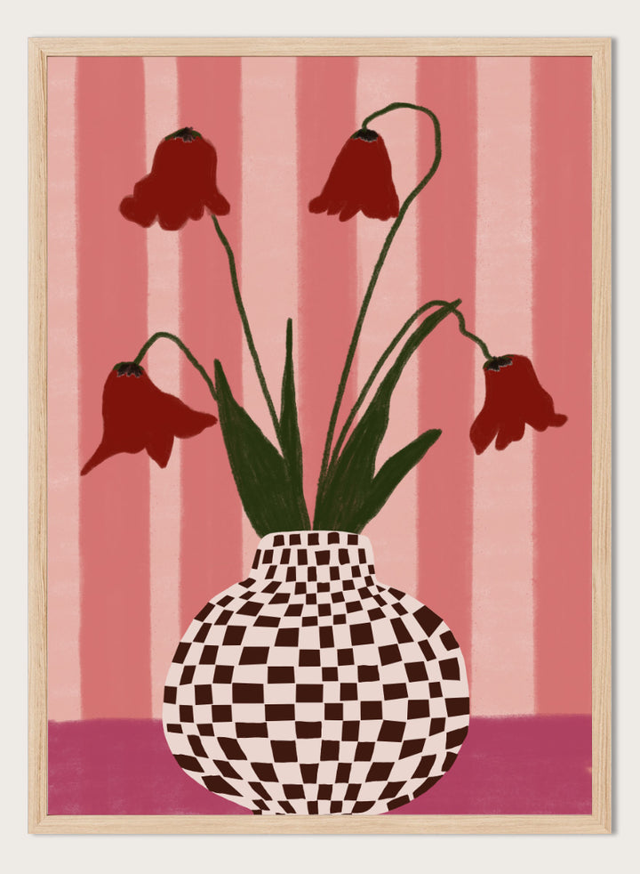 A stylized floral artwork showing four dark red bell-shaped flowers with long green stems rising from a black-and-white checkerboard vase, set against pink vertical stripes and a pink base. Whimsical Flowers Checkered Vase by The Art Concept still life art print featuring red flowers, a checkered vase, and a soft pink striped background.