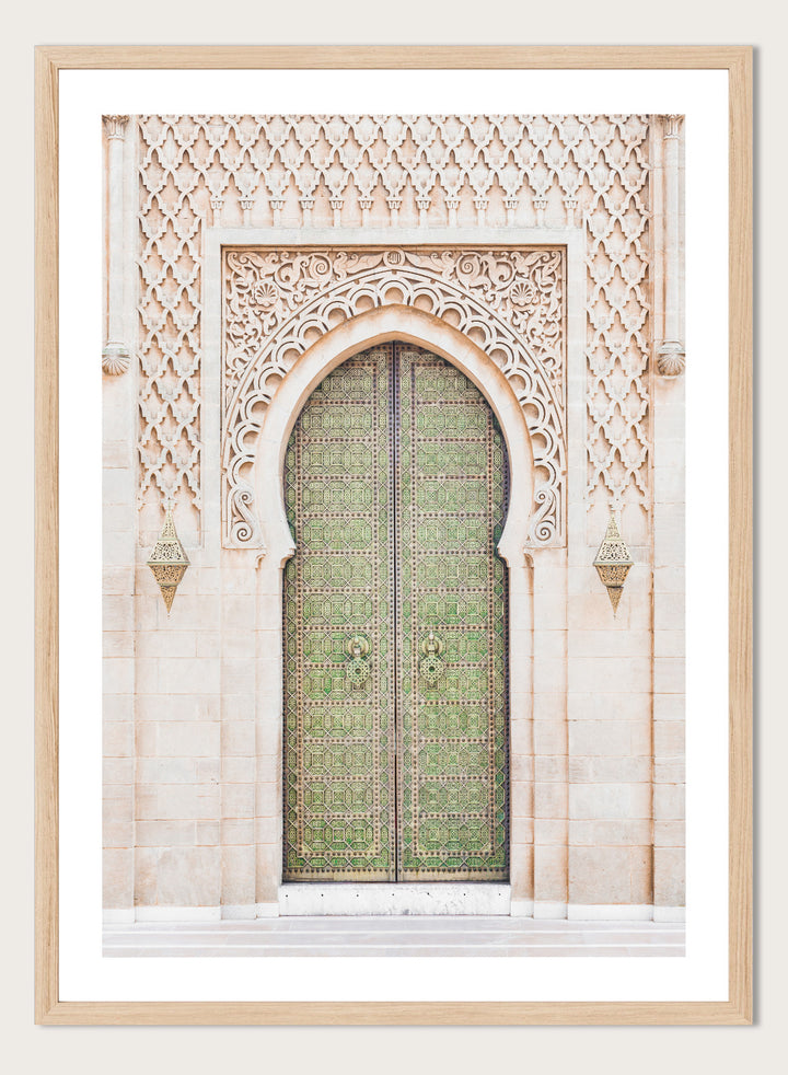 Decorative archway with ornate green door on a light stone wall. Ornate Moroccan Green Door by Henrike Schenk is a Moroccan architecture print featuring an ornate green door, Islamic patterns, and historic stone details.