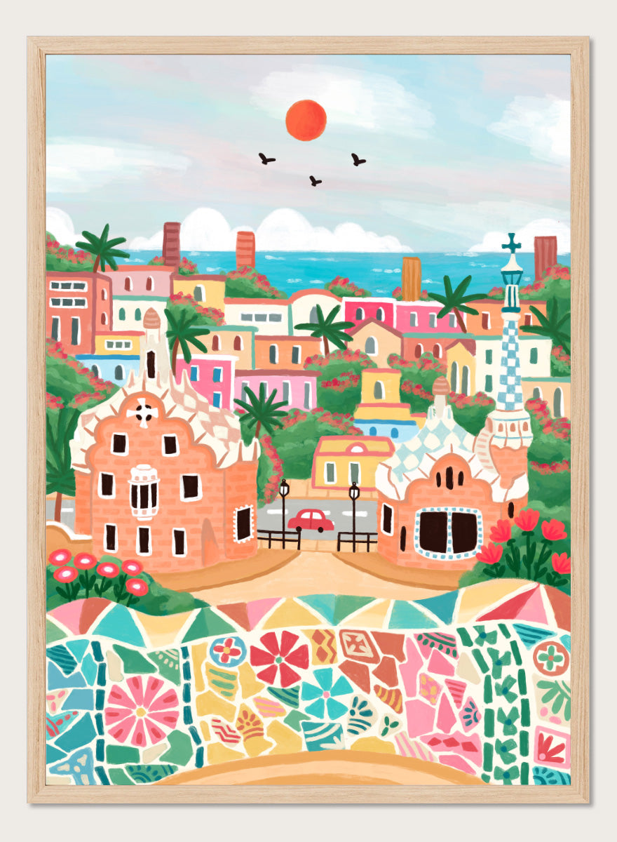 A colorful stylized illustration of a coastal town with pastel buildings, palm trees, a mosaic wall in the foreground, blue sea, and a red sun in the sky. Shop Colorful Coastal Dream by Nidhi Kachhadiya, a vibrant Barcelona wall art print inspired by Park Güell, Gaudí architecture, mosaics, and bright coastal color.