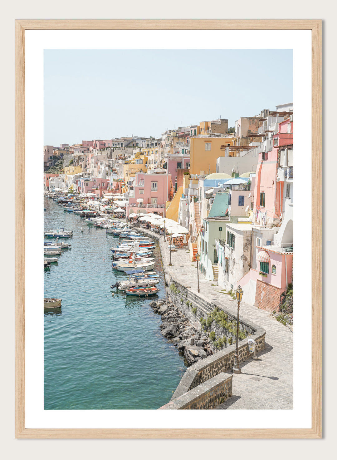 Colorful coastal town with boats docked along a waterfront. Colorful Italian Harbor by Henrike Schenk is a coastal photography print featuring pastel waterfront architecture, fishing boats, turquoise waters, and Mediterranean charm.