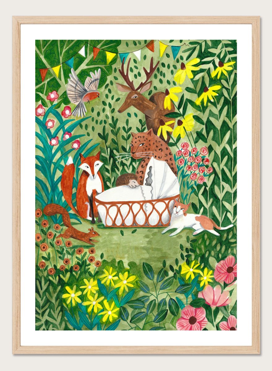 A framed art print featuring a whimsical forest illustration with animals gathered around a basket, surrounded by flowers and foliage. The print is shown with a white mat and a black frame against a white background. Welcome to the Forest by Caroline Bonne Müller woodland animal art print featuring a baby surrounded by a leopard, fox, deer, cat, flowers, and forest life.