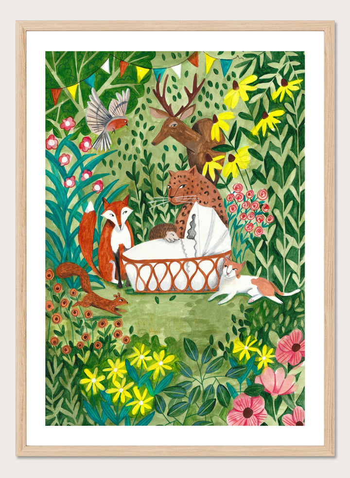 A framed art print featuring a whimsical forest illustration with animals gathered around a basket, surrounded by flowers and foliage. The print is shown with a white mat and a black frame against a white background. Welcome to the Forest by Caroline Bonne Müller woodland animal art print featuring a baby surrounded by a leopard, fox, deer, cat, flowers, and forest life.