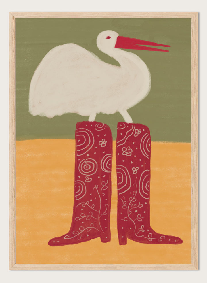 A stylized art print featuring a white stork with a red beak standing on a pair of tall red boots with white swirl patterns, set against a muted green and ochre background. Bird in Red Boots by The Art Concept playful animal art print featuring a white bird in oversized red patterned boots with soft green and ochre tones.