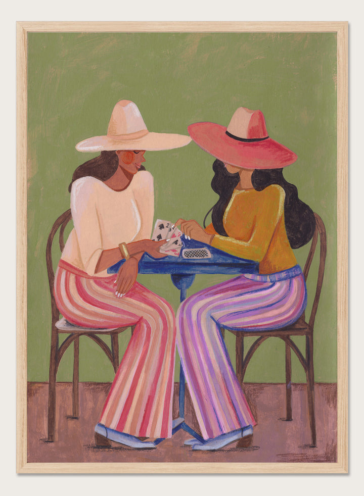 Two women playing cards at a table with colorful clothing and hats against a green background. Stylish Women Play Cards by Caroline Bonne Müller is a fine art print and wall poster featuring two fashionable women playing cards at a table.
