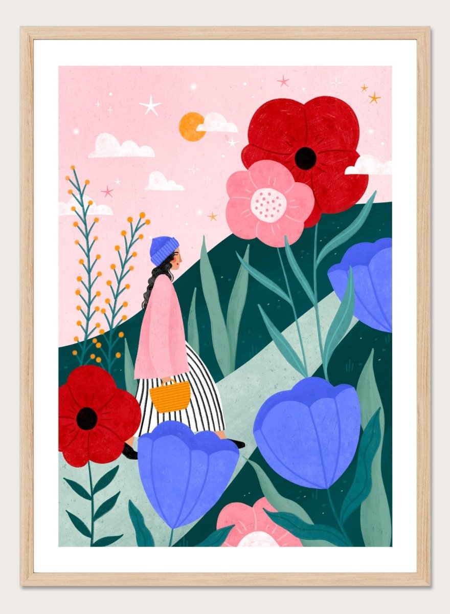 A framed art print featuring a whimsical, colorful illustration of a woman walking through a field of oversized flowers under a pink sky with moon. Whimsical Flower Path by Bea Müller premium fine art print featuring a woman walking among oversized flowers in a bright, playful landscape.