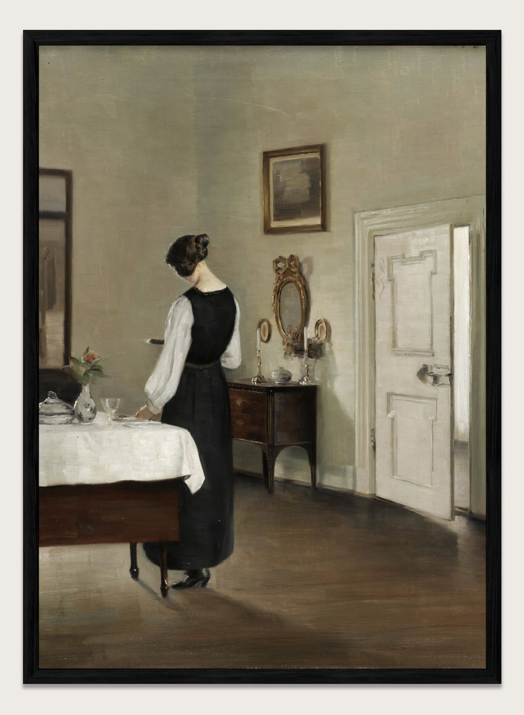 Woman in a black dress standing in a room with a table and mirror. In the Dining Room by Carl Holsøe is a vintage Danish interior art print featuring a woman in a softly lit dining room with muted tones and classic Scandinavian style.