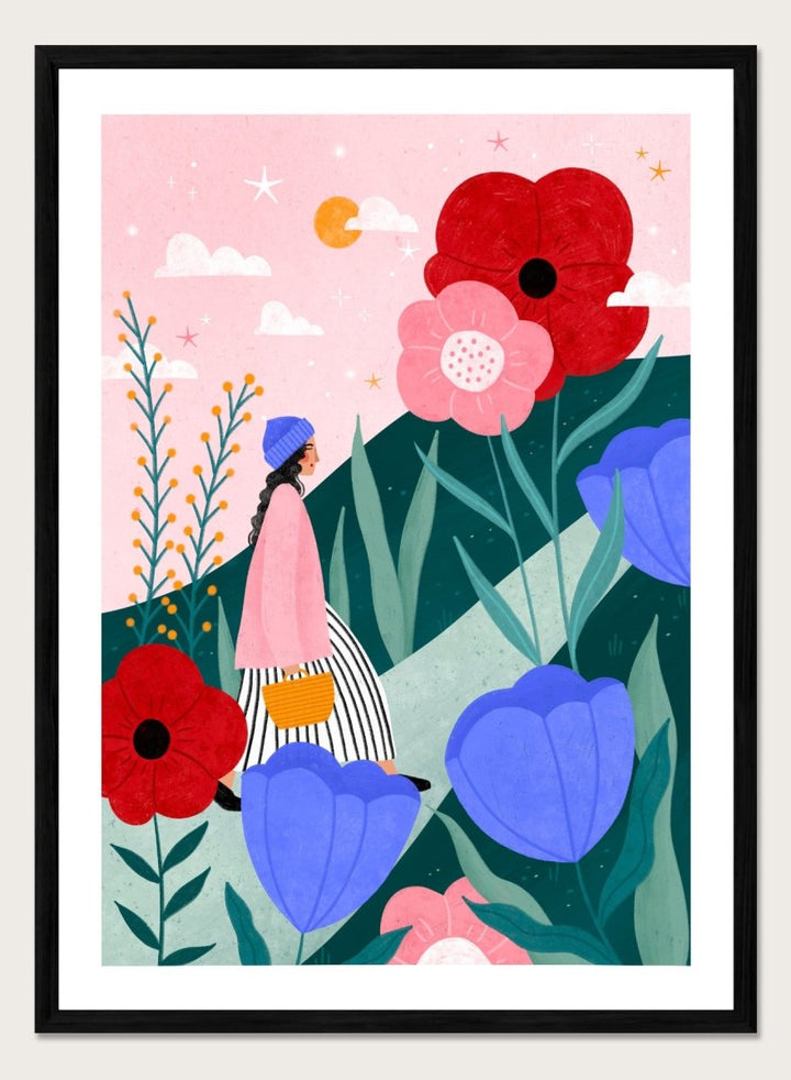 A framed art print featuring a whimsical, colorful illustration of a woman walking through a field of oversized flowers under a pink sky with moon. Whimsical Flower Path by Bea Müller premium fine art print featuring a woman walking among oversized flowers in a bright, playful landscape.