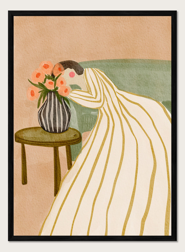 A stylized art print depicting a woman in a cream and gold striped gown leaning over a small table with a striped vase of pink flowers, set against a muted green sofa and beige background. Shop Woman Admiring Flowers by Nikita Jariwala, a modern floral wall art print featuring a woman, peach blooms, striped dress, and warm earthy tones.