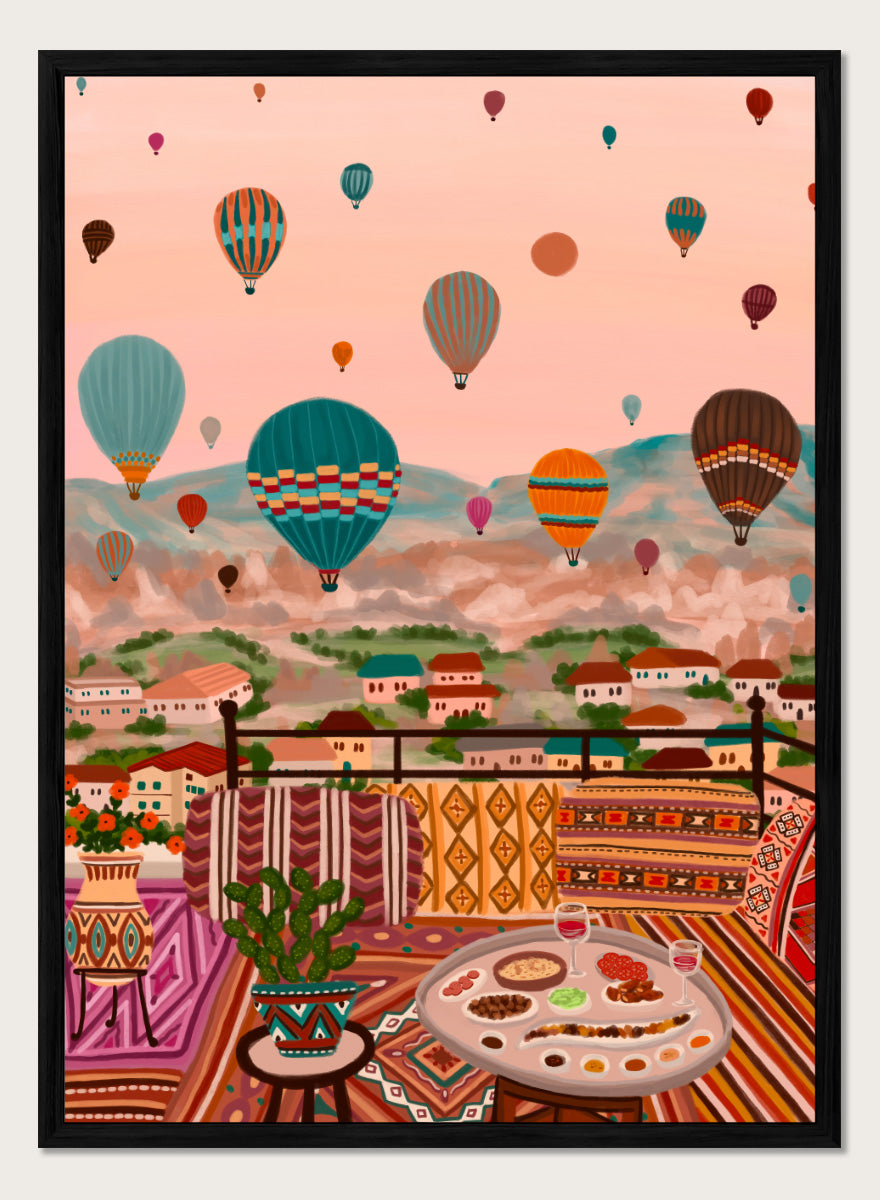 A colorful art print depicting a scenic view of a hillside town with mountains in the background, filled with hot air balloons. In the foreground, a patterned outdoor seating area features a table with food and a potted plant. Shop Balloons Over Rooftop Dinner by Nidhi Kachhadiya, a colorful travel wall art print featuring hot air balloons, rooftop dining, patterned textiles, and teal and coral tones.