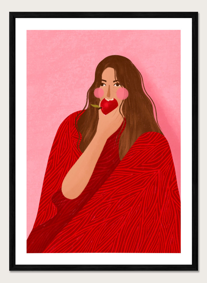 A framed art print featuring a stylized illustration of a woman with long brown hair, wearing a red patterned wrap, holding a red apple to her lips, set against a pink background. Cozy Woman Apple by Bea Müller portrait art print featuring a woman eating a red apple in bold red and pink tones for colorful modern wall decor.