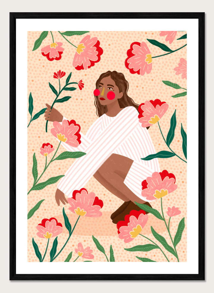 A framed art print featuring a stylized illustration of a woman in a white striped sweater surrounded by pink and red flowers on a peach background. Woman in Floral Garden by Bea Müller floral art print featuring a woman surrounded by oversized pink flowers, green leaves, and playful botanical details.