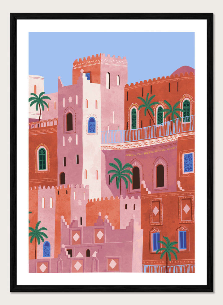 A framed art print featuring a stylized illustration of Moroccan-style buildings in shades of terracotta, pink, and cream, accented with green palm trees and blue window details, set against a light blue sky. Vibrant Moroccan City by Ceyda Alasar travel art print featuring layered terracotta architecture, arched windows, palms, and colorful Moroccan details.